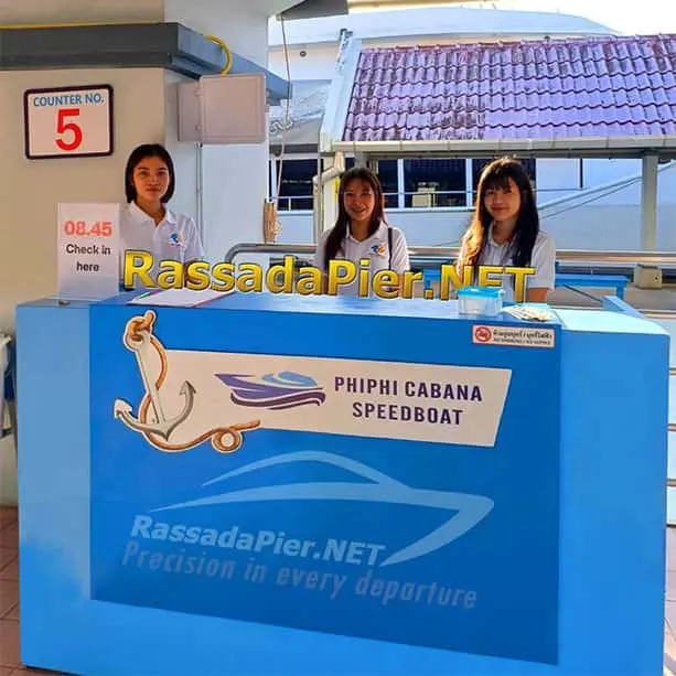 Three friendly staff members welcoming passengers at Rassada Pier Counter No. 5 for the 08:45 Phi Phi Cabana speedboat check-in